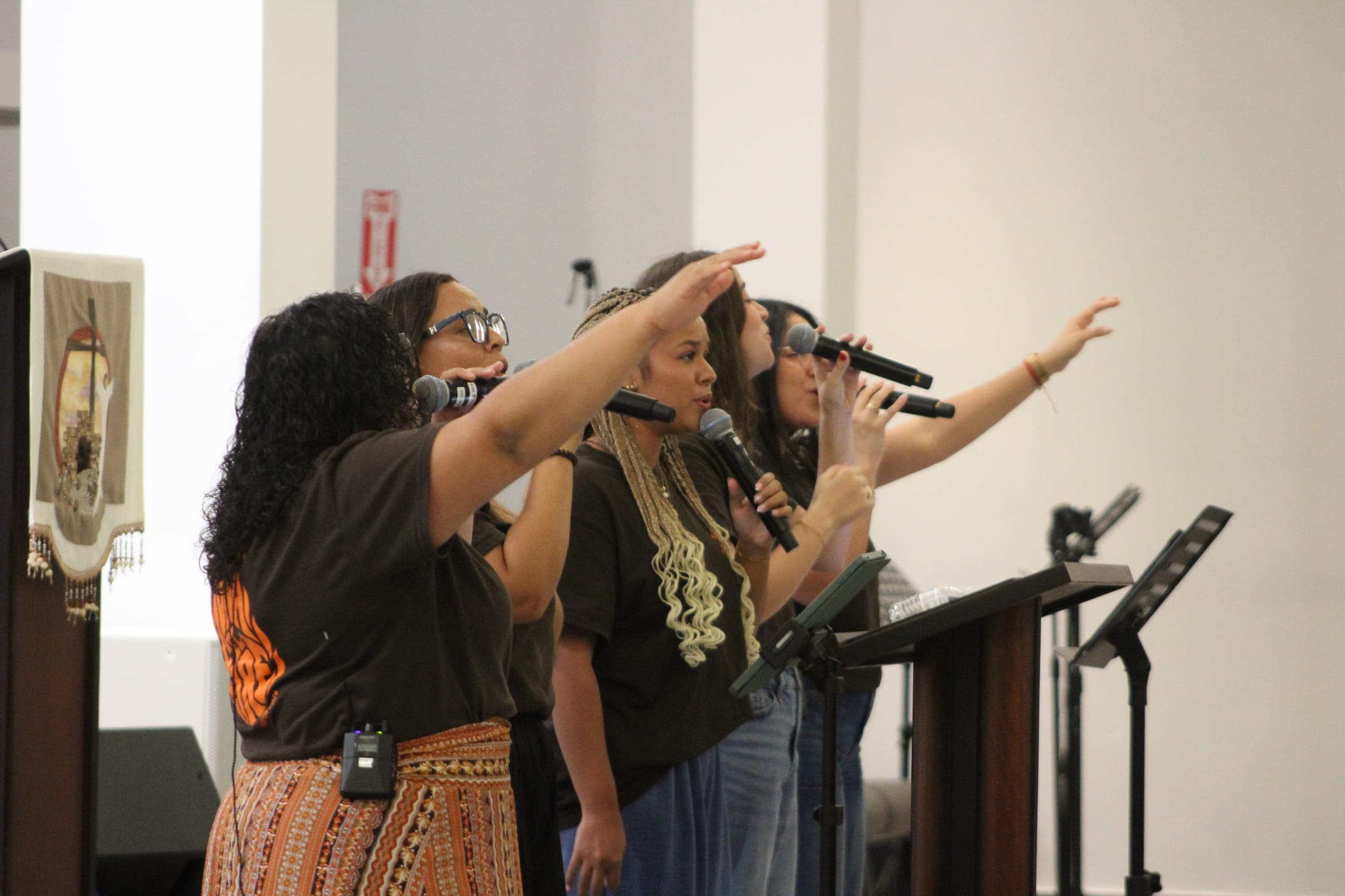 Jóvenes del grupo de alabanza cantando con los brazos alzados.