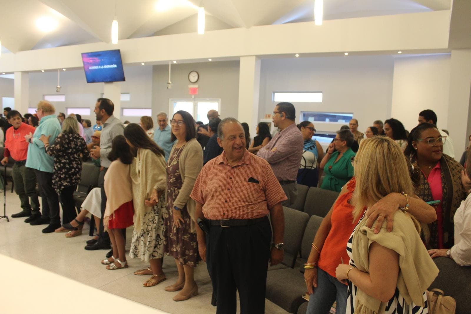 Miembros de la congregación de pie, sonriendo, durante el culto.