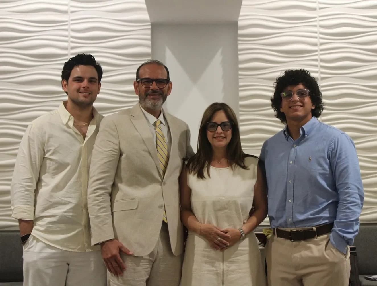 La familia pastoral posa sonriendo frente a la pared del templo.