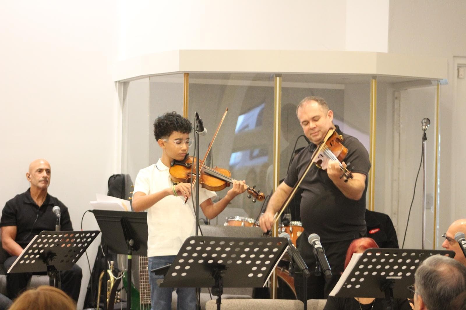 Un joven y un adulto tocan el violín juntos.