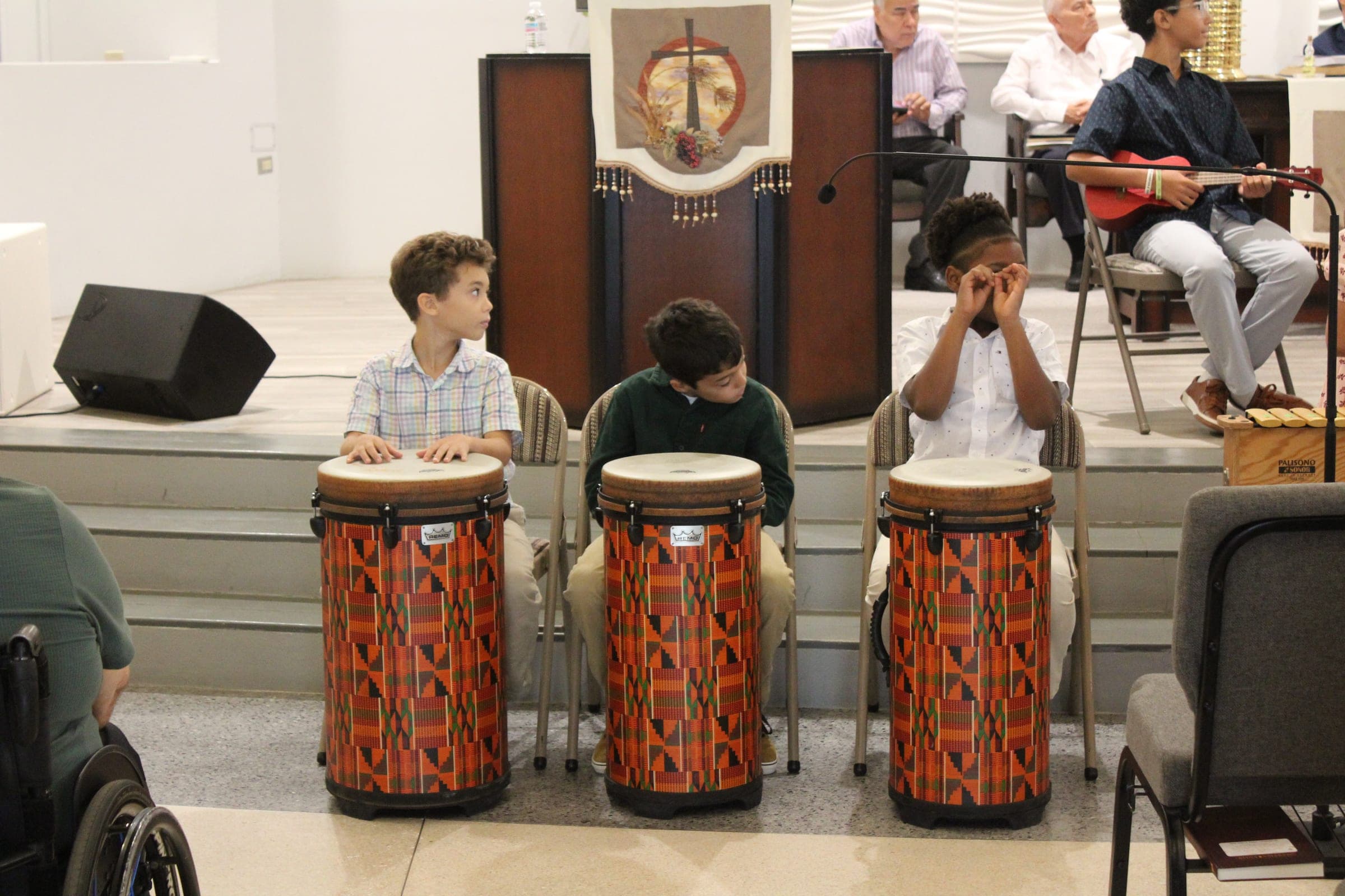 Tres niños tocando tambores durante el culto.